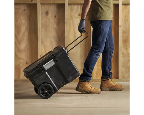 En person drar en svart verktygslåda med hjul och teleskophandtag.