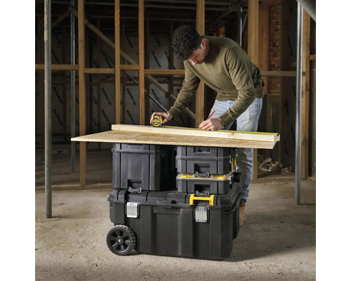 Man mäter en träplanka med ett rullbandmått på en verktygslåda