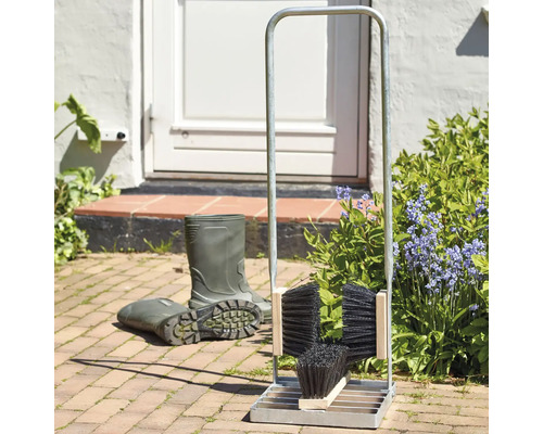 Stövelställ med borstar och gummistövlar framför ett hus