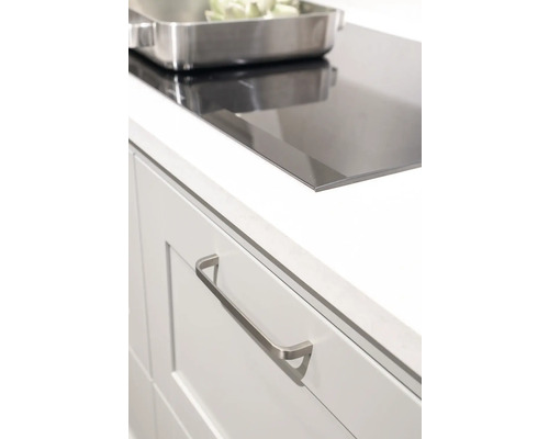 Detaljbild av ett modernt kök med spishäll, lådor och köksredskap.