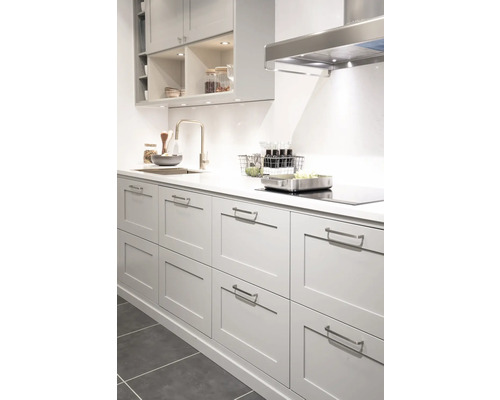 Ljust kök med diskho, blandare, spishäll och fläkt