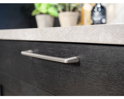 Detaljbild av en mörk lådfront med silverfärgat handtag