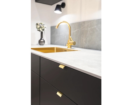 Detaljbild av diskho med blandare, bänkskiva och lådfronter.