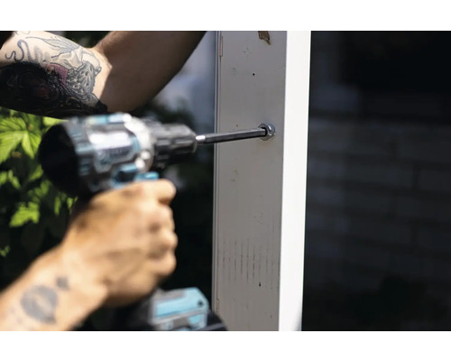 En person skruvar en skruv i en stolpe med en sladdlös skruvdragare.