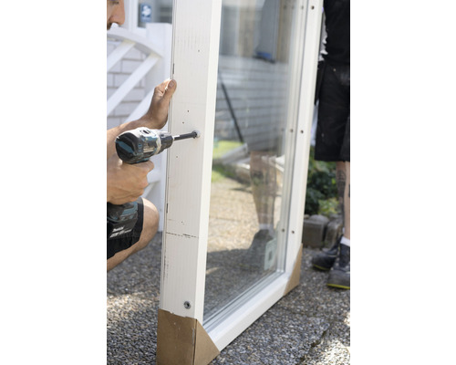 Hantverkare monterar fönster med en sladdlös skruvdragare