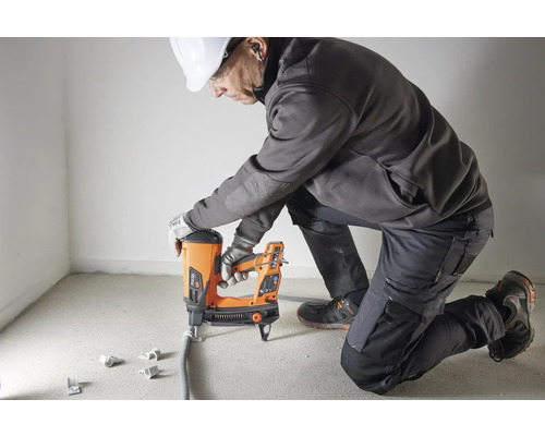 Hantverkare fäster en elkabel på en vägg med en bultpistol