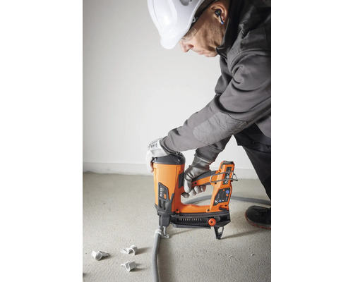 Hantverkare fäster ett rör med en bultpistol.