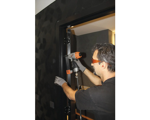 Hantverkare fäster en dörrkarm med en tryckluftsdriven spikpistol.