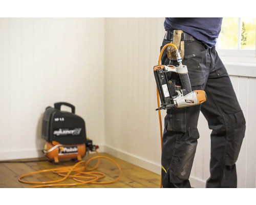 Hantverkare med spikpistol på bältet och kompressor på golvet