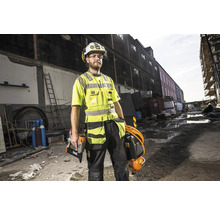 En byggnadsarbetare bär skyddskläder och verktyg på en byggarbetsplats.