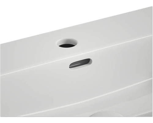 Detaljvy av ett tvättställ med blandarhål och överfyllnadsskydd