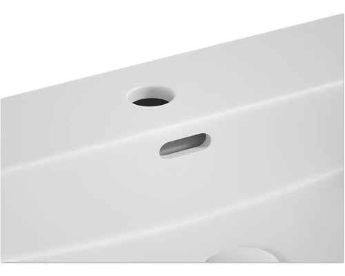 Detaljvy av ett tvättställ med blandarhål och överlopp