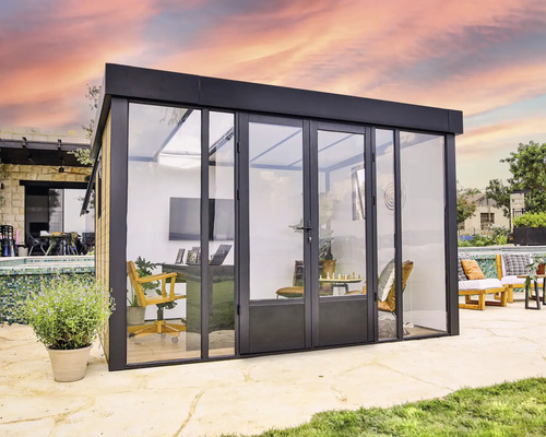 Modernt trädgårdskontor med glasfront och skjutdörrar, utrustat med kontorsmöbler och dekorativa element