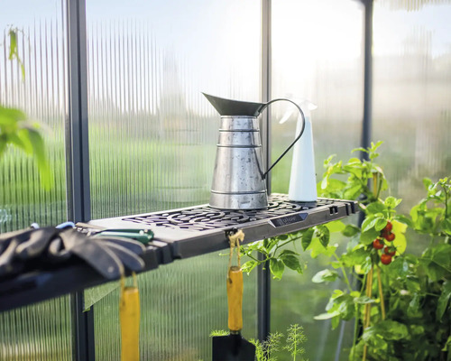 Hylla i växthus med vattenkanna, sprayflaska och trädgårdsredskap