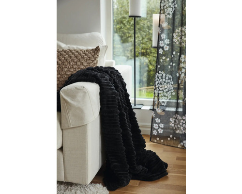 Dekorativt vardagsrum med soffa, kuddar, överkast, golvlampa och gardin