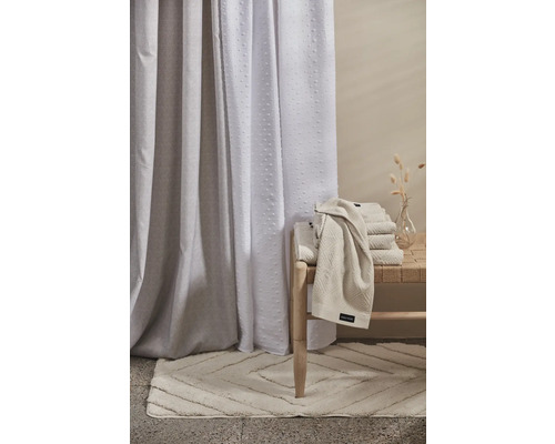 Badrumsscen med duschdraperi, badrumsmatta och handdukar på en bänk