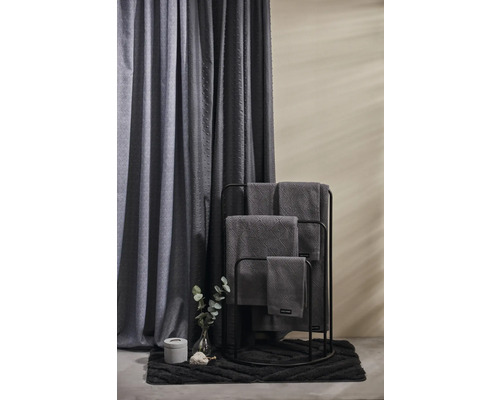 Badrumsscen med handduksställ, handdukar, duschdraperi, badrumsmatta och dekoration