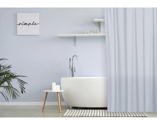 Ljust badrum med fristående badkar, duschdraperi och dekorativa element