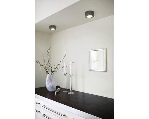 Två taklampor lyser upp ett rum med en byrå, dekoration och en inramad bild.