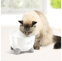 En katt dricker ur en vattenfontän för katter i kattdesign.