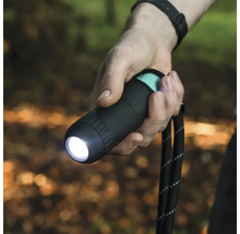 En person håller i en svart ficklampa med handledsrem.