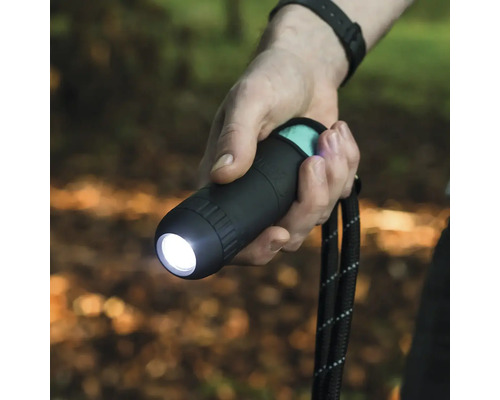 En person håller i en svart ficklampa med handledsrem.