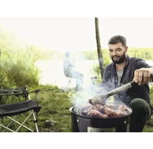 Man grillar kött utomhus med grilltång
