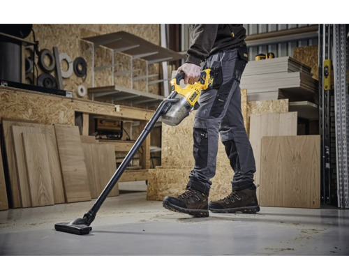 En arbetare använder en sladdlös dammsugare från DeWalt i en verkstad.
