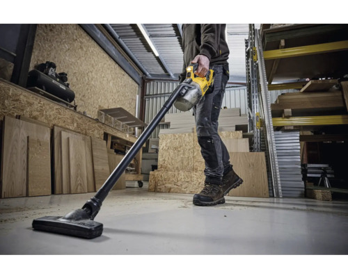 Man använder en sladdlös dammsugare från DeWalt i en verkstad.