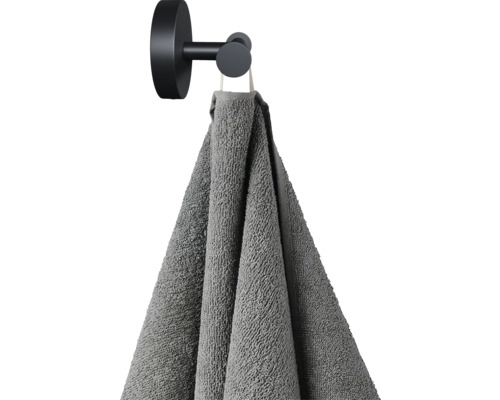Grå handduk hänger på en svart handdukskrok