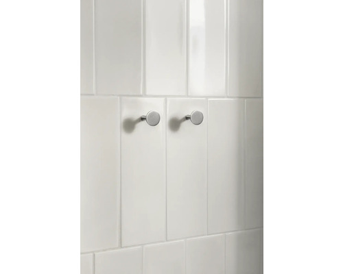 Två runda klädkrokar av metall på en kakelvägg.