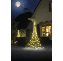 Belyst julgran i trädgården framför huset på natten