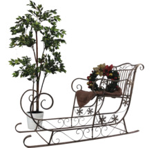 Dekorativ scen med konstgjort träd i kruka och dekorativ släde med julkrans.