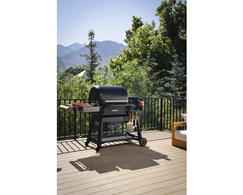 Kolgrill på en terrass med utsikt över trädgården.