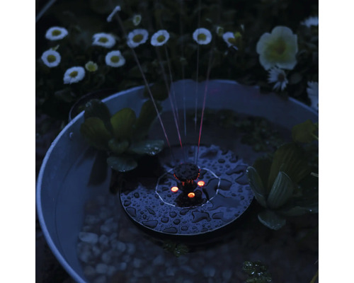 Solcellsdriven fontän i trädgårdsdammen med vattenväxter