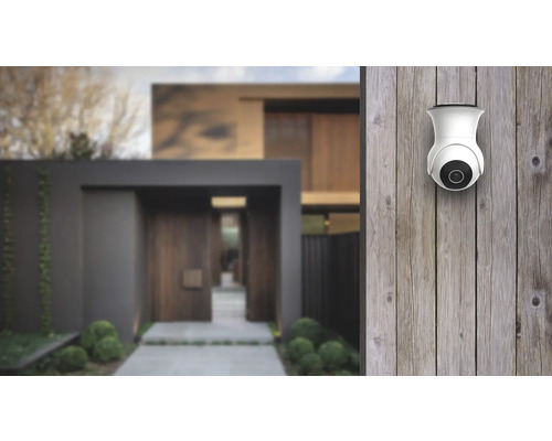 Övervakningskamera på trävägg framför ett hus