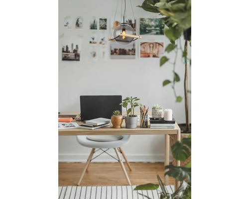 Kontorsarbetsplats med skrivbord, stol, lampa, bärbar dator, anteckningsböcker och växter