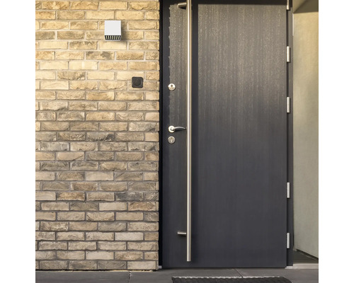 Utomhusbild av en ytterdörr med handtag och en utomhuslampa på en tegelvägg