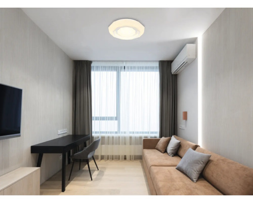 Vardagsrum med taklampa, soffa, skrivbord och gardiner