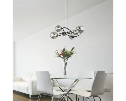 Modern pendellampa med flera sfäriska lampskärmar ovanför ett matbord i ett ljust rum.