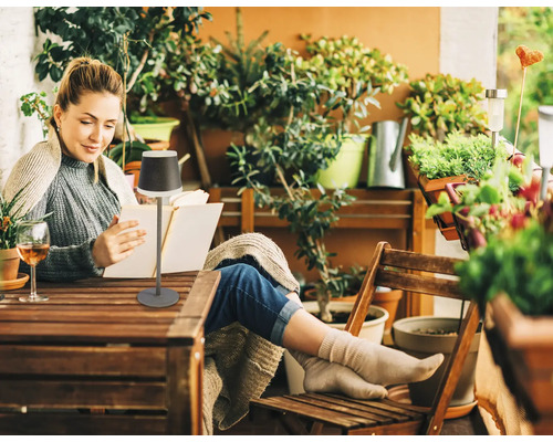 Kvinna läser bok på balkongen med en bordslampa
