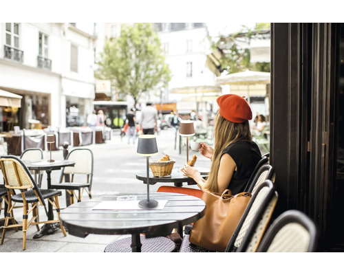 Scen från ett gatucafé med bord och bordslampor.