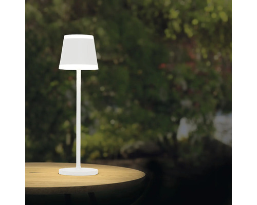 Vit bordslampa på ett bord i trädgården.