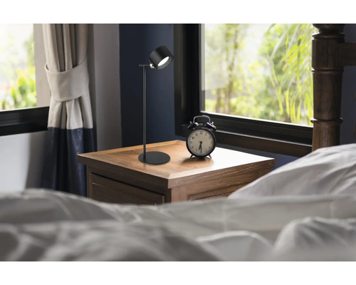 Sovrum med sänglampa och väckarklocka på ett sängbord