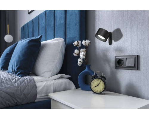 Sovrum med säng, sängbord, vägglampa och eluttag