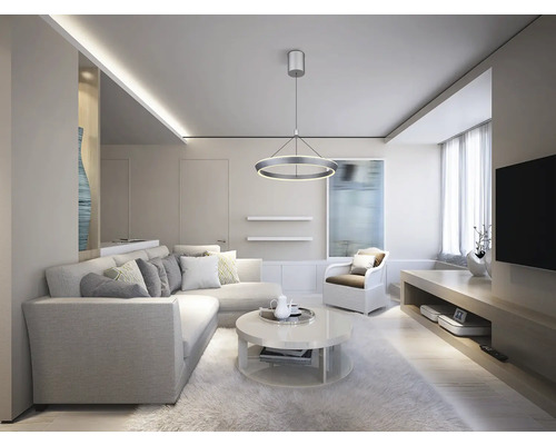 Ljust vardagsrum med hörnsoffa, runt soffbord, fåtölj och ringformad taklampa