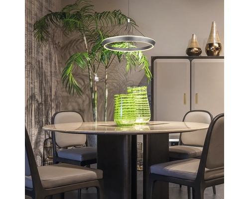 Matsal med runt bord, stolar, hänglampa och dekorativa vaser