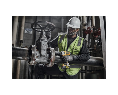 En arbetare i skyddskläder använder en sladdlös mutterdragare på ett rör.