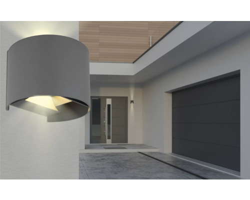 Modern husfasad med grå garageport, ytterdörr och rund vägglampa