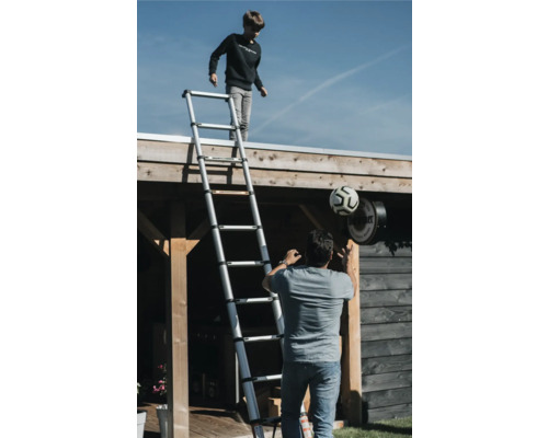 Utomhusscen med en pojke på en teleskopisk stege och en man med en fotboll.